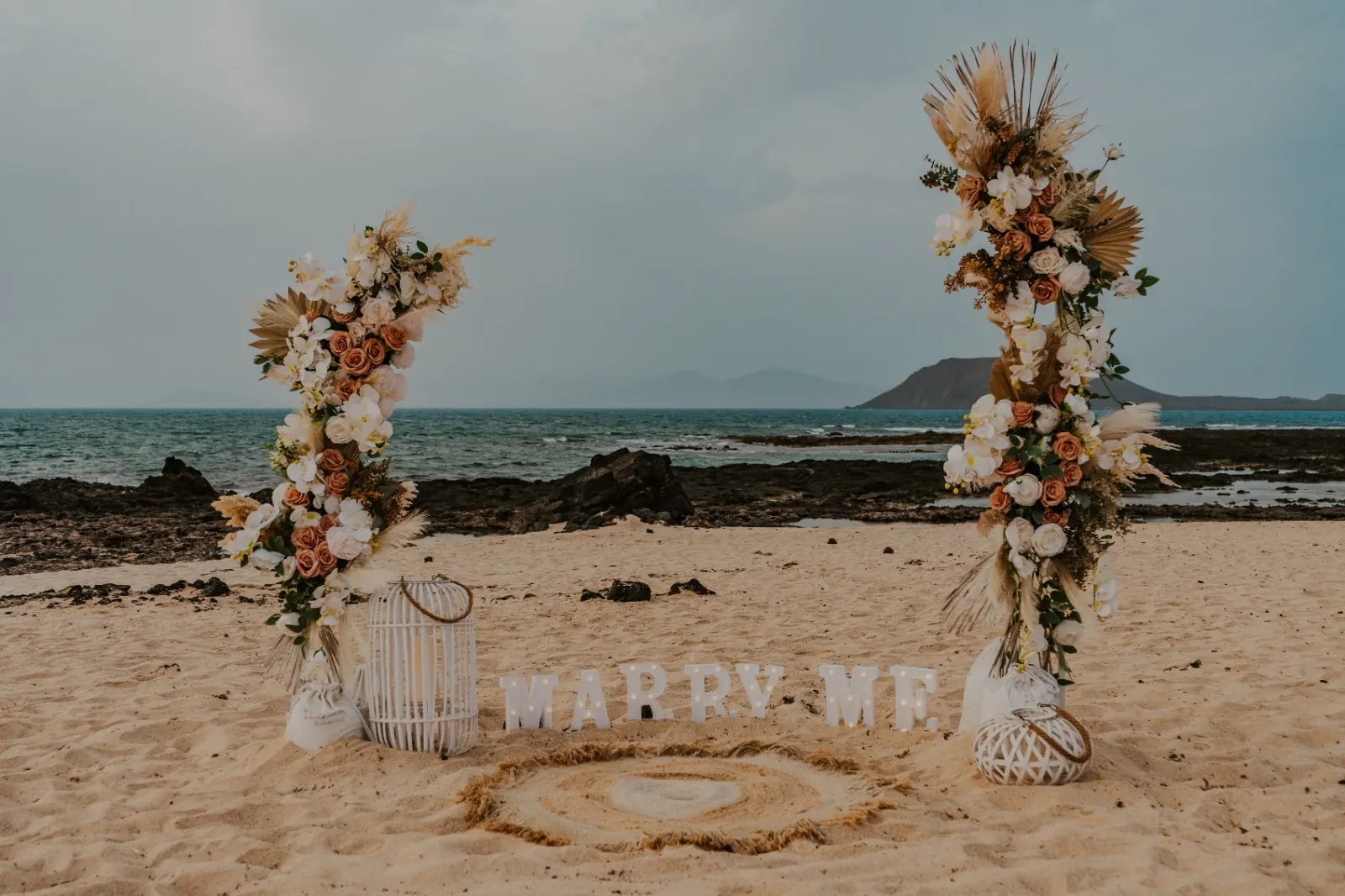 Arco floreale in spiaggia con scritta luminosa Marry Me