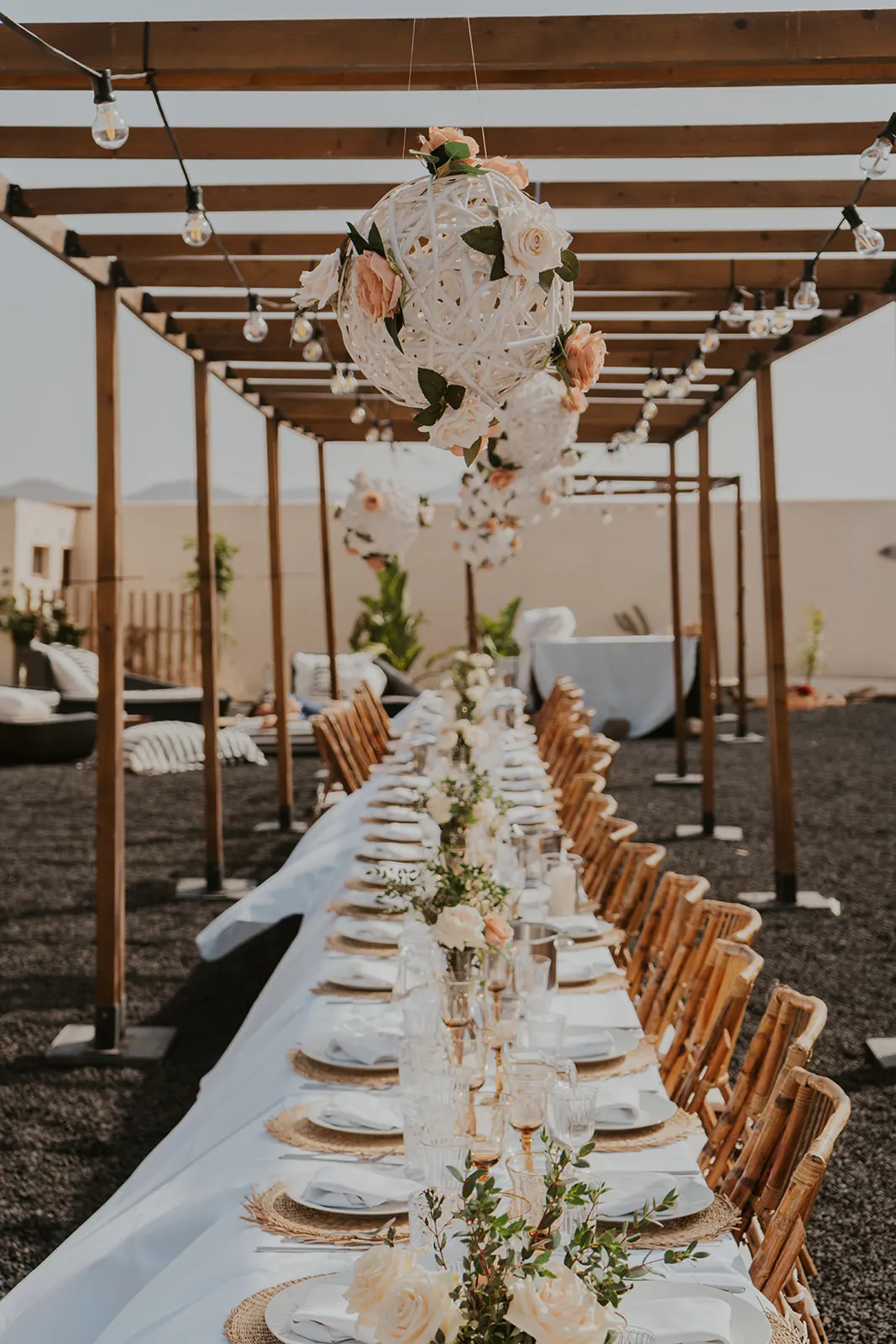 Pergola di legno con tavolo lungo decorato con sfere di fiori bianchi e rosa per un evento privato