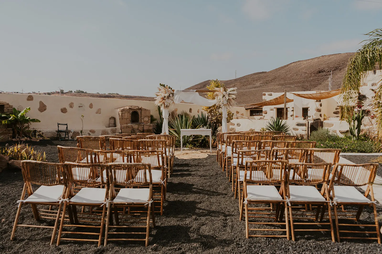 Cerimonia in tenuta con arco floreale bianco e sedie in rattan